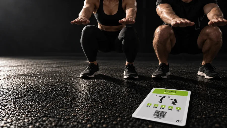 Zwei Spieler in der tiefen Kniebeuge auf einem schwarzen Hallenboden, vorn liegt die Challenge-Karte Squats